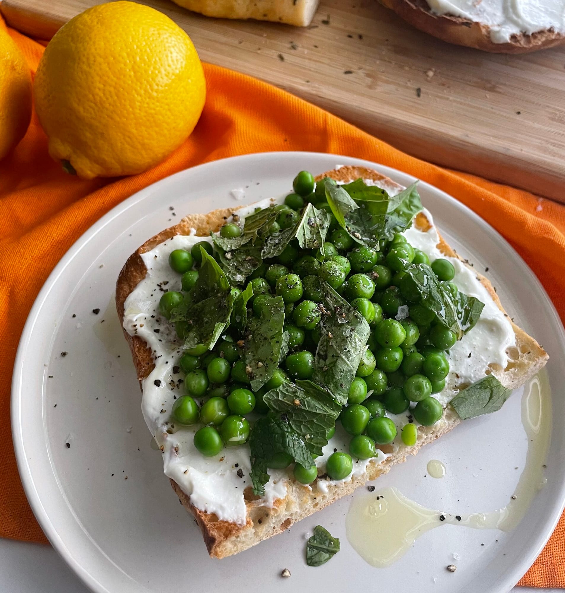 toast with a layer of ricotta cheese, topped with fresh peas and fresh herbs