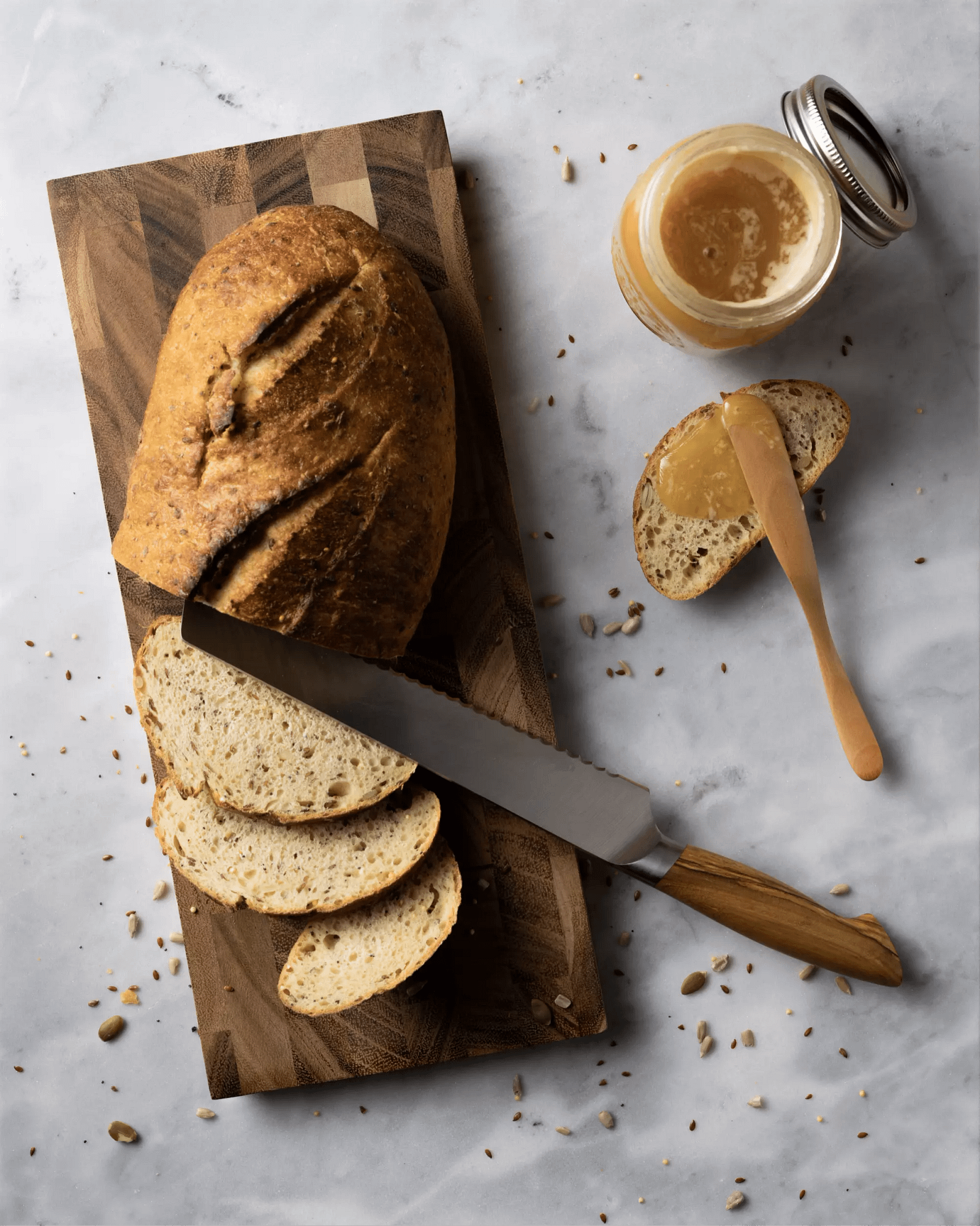 Par baked Lucky 7 Multigrain batard sliced on a wooden cutting board