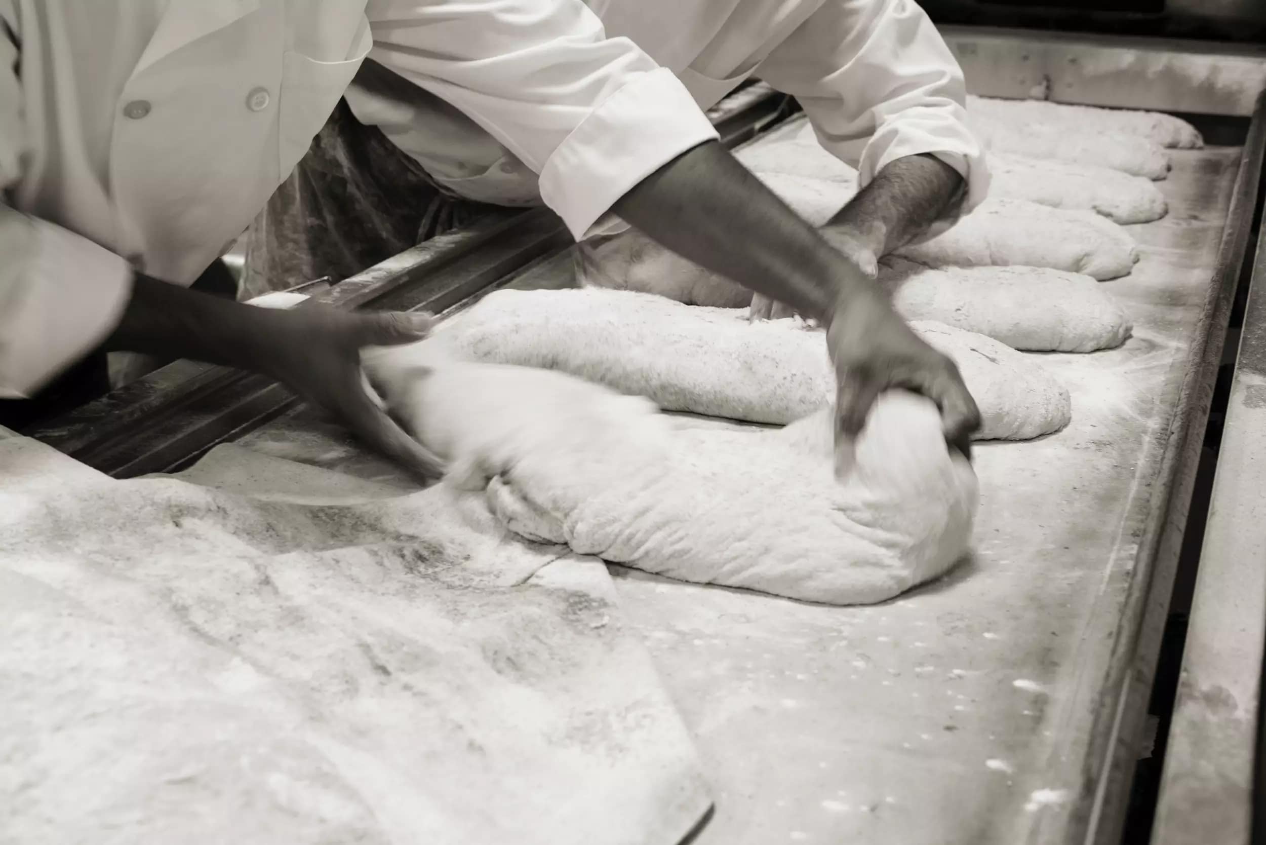 Baker's working bread dough into loaves
